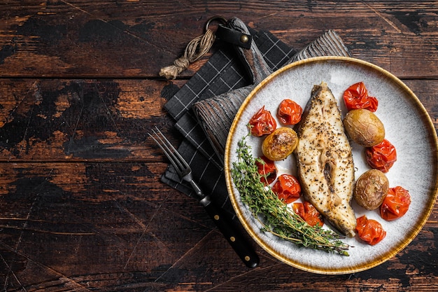 Gegrilde heilbot vissteaks met tomaat en aardappel in plaat Houten achtergrond Bovenaanzicht Kopieer ruimte