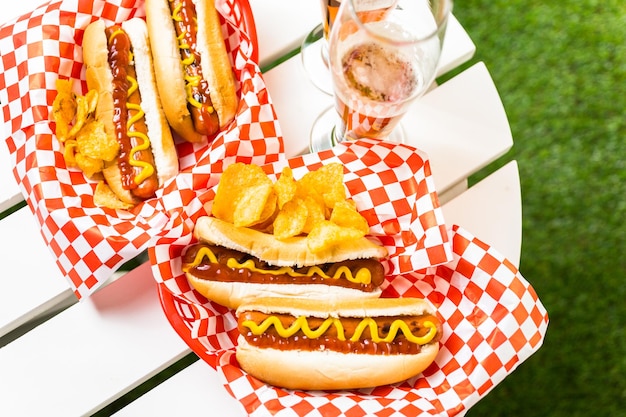 Gegrilde hotdogs met mosterd en ketchup op tafel met bier van de tap.