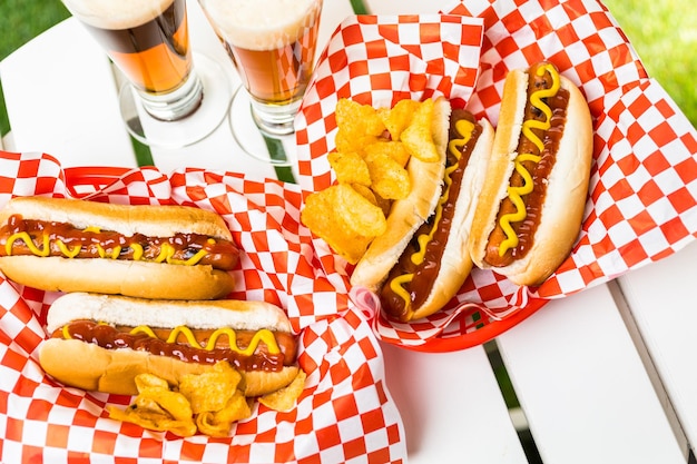 Gegrilde hotdogs met mosterd en ketchup op tafel met bier van de tap.