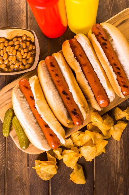 Gegrilde hotdogs op een witte hotdogbroodjes met chips en gebakken bonen aan de zijkant.