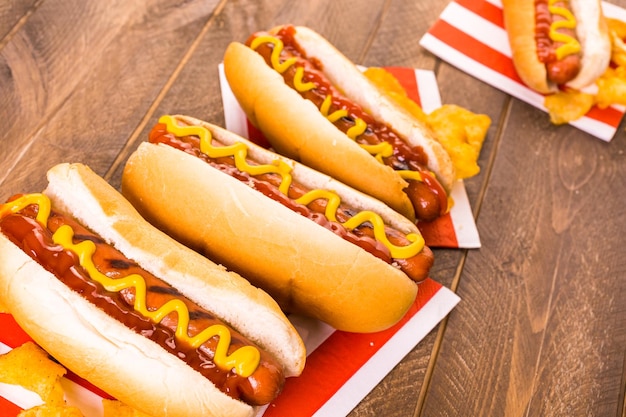 Gegrilde hotdogs op een witte hotdogbroodjes met mosterd en ketchup.