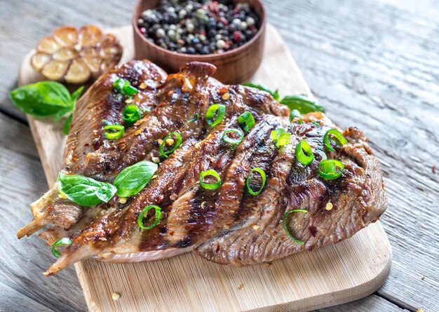 Gegrilde kalkoen met groene lente-ui op de houten plank