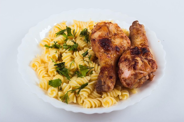 Gegrilde kip drumstick en pasta op witte plaat witte achtergrond