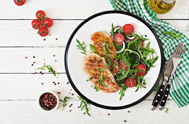 Gegrilde kipfilet en verse groentesalade van tomaten, rode ui en rucola.