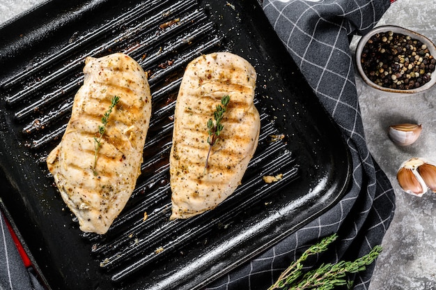 Gegrilde kipfilet in een pan met tijm en knoflook. grijze achtergrond. Bovenaanzicht