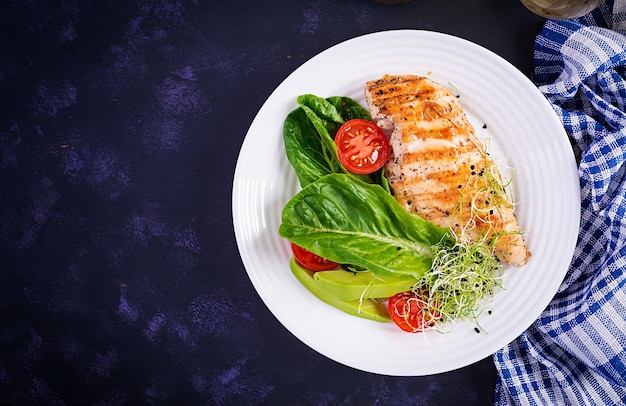 Gegrilde kipfilet met salade, verse tomaten en avocado.