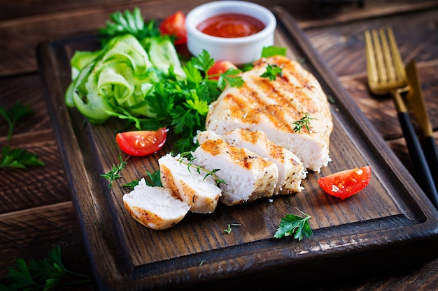 Gegrilde kipfilet met verse groenten op houten snijplank. Gezond diner. Kopieer ruimte