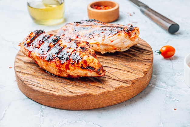 Gegrilde kipfilets op houten snijplank over grijze marmeren achtergrond