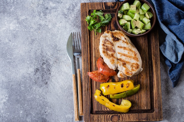 Gegrilde kippenborst met tomaat en peper grill en salsa van avocado op een houten bord