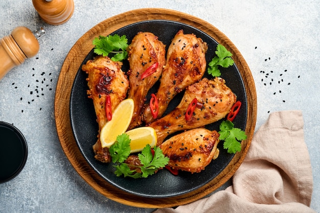 Gegrilde kippenboutjes of poten of geroosterde bbq met kruiden en tomatensalsasaus op lichtgrijs betonnen oppervlak. Bovenaanzicht