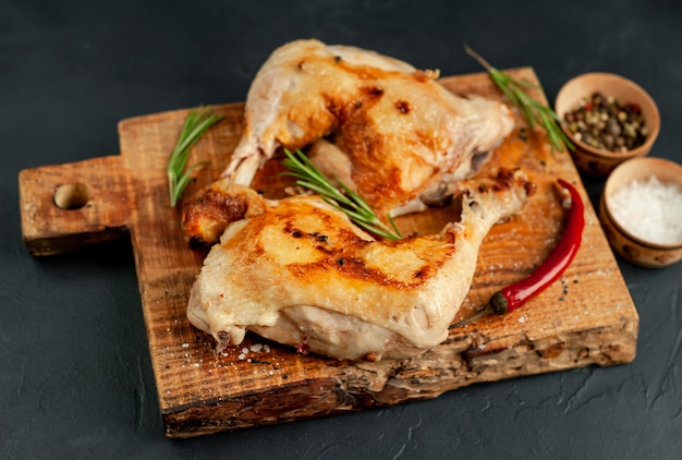 gegrilde kippenpoten met specerijen en kruiden, klaar voor het koken op een stenen achtergrond.