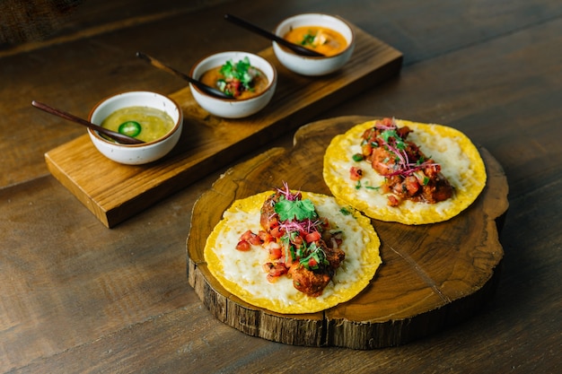 Gegrilde kippentaco&#39;s met tomatensalade geserveerd op houten snijplank met sauzen