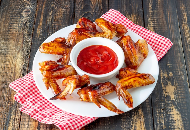 Gegrilde kippenvleugels en rode saus op een houten achtergrond. Snack tot bier. Barbecue. Recepten.