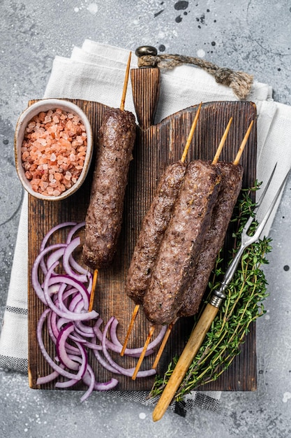 Gegrilde kofta kofte shish kebab van gehakt lam en rundvlees op spies grijze achtergrond bovenaanzicht