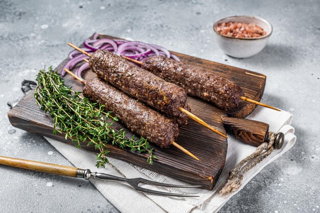 Gegrilde kofta kofte shish kebab van gehakt lam en rundvlees op spies grijze achtergrond bovenaanzicht