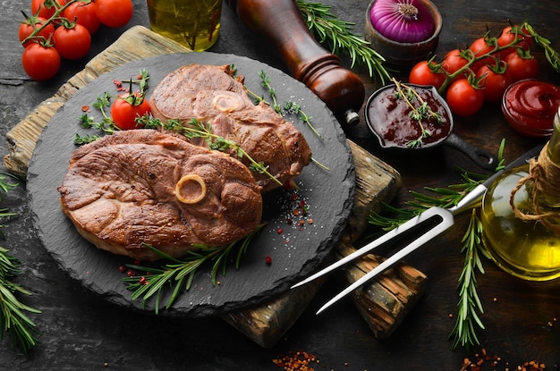 Gegrilde lamsbiefstuk met kruiden en rozemarijn. Barbecue vlees. Bovenaanzicht. Platliggend bovenaanzicht op zwarte stenen snijtafel.