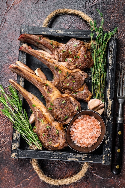 Gegrilde lamskoteletten steaks in een houten dienblad. Donkere achtergrond. Bovenaanzicht.