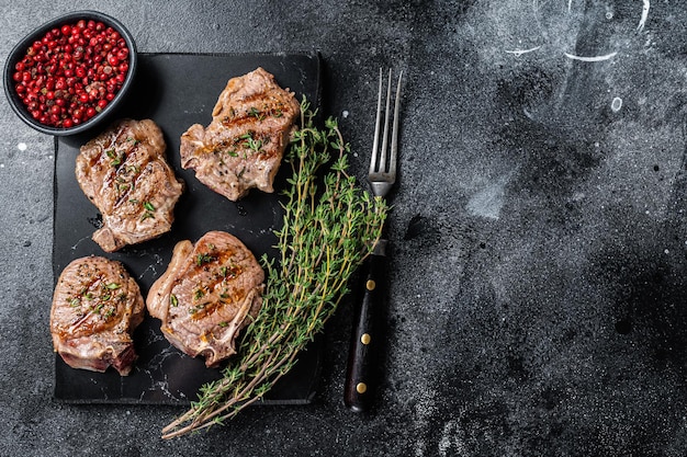 Gegrilde lamslende karbonades steaks schnitzels op een marmeren bord Zwarte achtergrond Bovenaanzicht Ruimte kopiëren