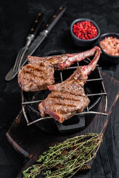 Gegrilde lamsvlees koteletten steaks op een grill. Zwarte achtergrond. Bovenaanzicht.