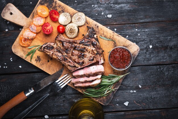 Gegrilde lendenstuk gesneden biefstuk op snijplank over stenen tafel. bovenaanzicht met kopie ruimte