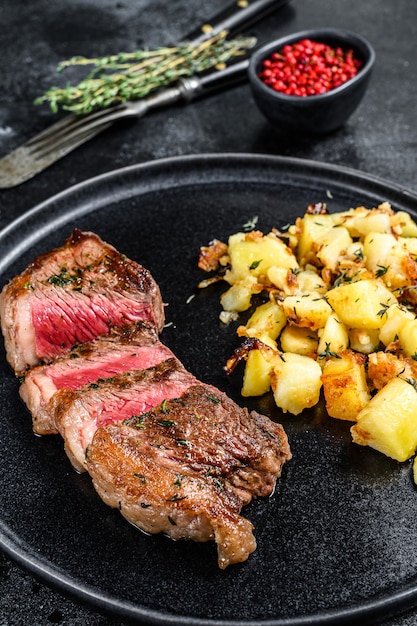 Gegrilde lendenstuk met aardappel, rundvlees. Zwarte achtergrond.