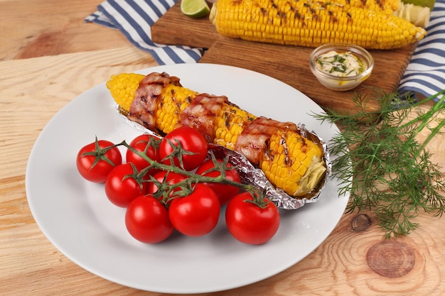 Gegrilde maïs met baken en kerstomaatjes op plaat