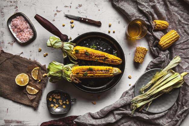 Gegrilde maïskolven met saus, coriande op oude armoedige houten witte achtergrond. Mexicaans eten. Bovenaanzicht. Kopieer ruimte, gezonde voeding, groenten