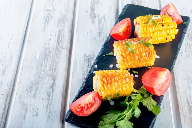 Gegrilde maïskolven met solt, specerijen en tomaten