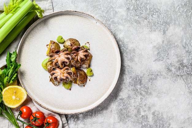 Gegrilde octopus met aardappelen en selderij. Grijze achtergrond. Bovenaanzicht Ruimte voor tekst