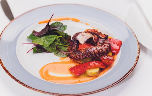 Gegrilde octopus met groenten en inktvissaus Restaurant lifestyle reisvoedsel gegrilde octopus met groenten Restaurantmenu Italiaanse verse zeevruchten