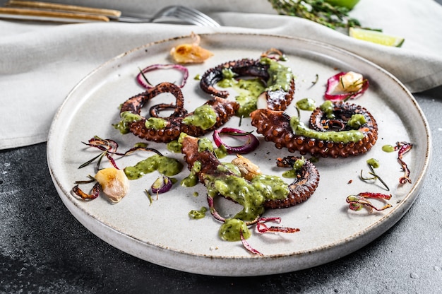 Gegrilde octopustentakels met pesto, tijm en ui. vers zee-eten. zwart oppervlak. bovenaanzicht