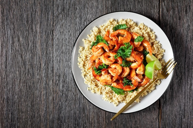 Gegrilde pittige garnalen geserveerd met gesneden avocado en quinoa boerenkoolsalade op een bord met bestek plat vrije ruimte