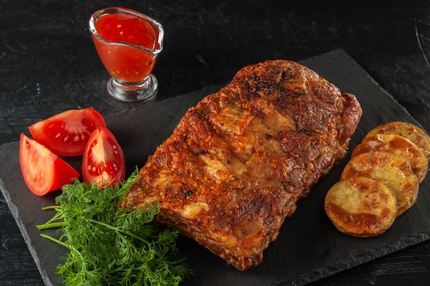 Gegrilde pittige ribben geserveerd met hete chilisaus en verse tomaten