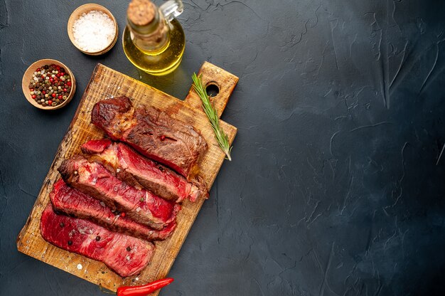 Gegrilde rib eye biefstuk met kruiden en specerijen op een stenen achtergrond met kopie ruimte voor uw tekst