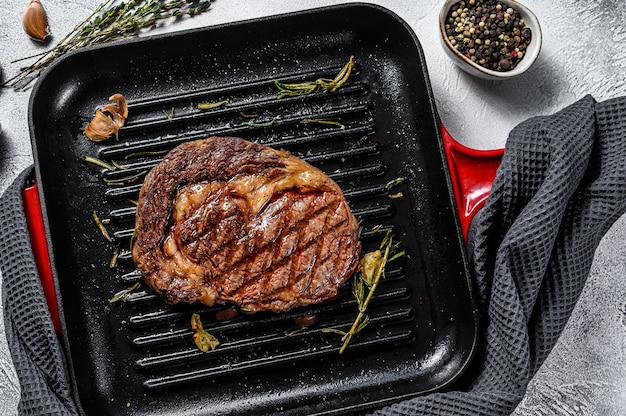 Gegrilde rib eye steak in een pan met rozemarijn en knoflook