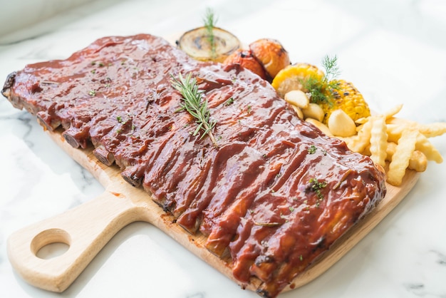 Gegrilde rib varkensvlees met barbecuesaus en groente en frech friet op houten snijplank