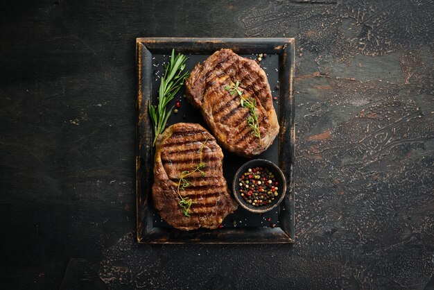 Gegrilde ribeye beef steak kruiden en specerijen op een donkere tafel Bovenaanzicht Vrije ruimte voor uw tekst