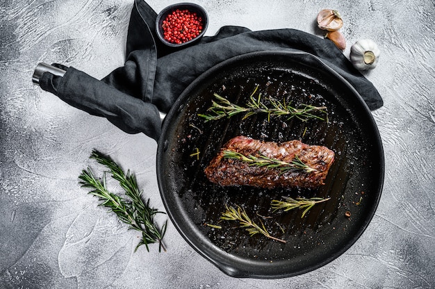 Gegrilde rok, machete steak in een koekenpan. Marmer vlees rundvlees. Grijze achtergrond. Bovenaanzicht