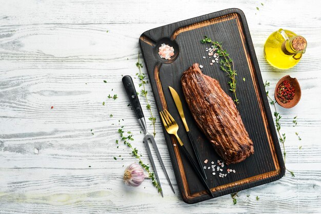 Gegrilde runderribeye steak, kruiden en specerijen. Bovenaanzicht met ruimte voor het kopiëren van tekst. Op een houten achtergrond.