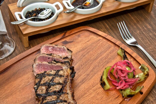 Foto gegrilde rundvlees steak in stukken gesneden met rode uien mexicaanse sauzen en een glas rode wijn voedsel