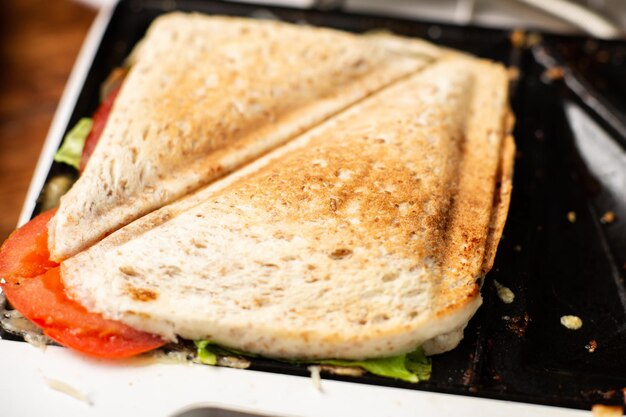 Gegrilde sandwich met kruiden en tomaat gekookt in een close-up van een tosti-ijzer