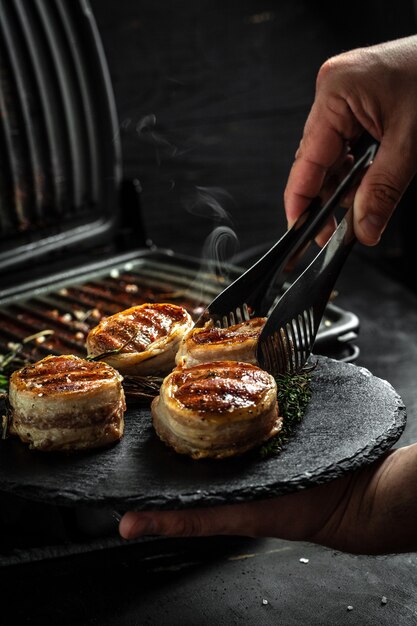 Gegrilde steak filet mignon verpakt spek door chef-kok handen. Restaurantmenu, diëten, kookboekrecept.