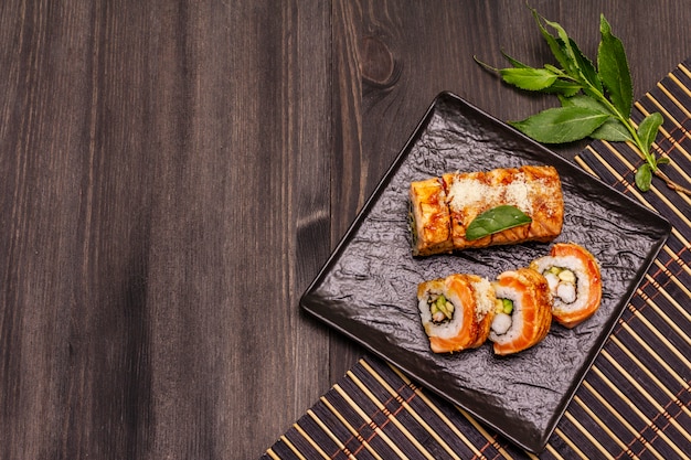 Gegrilde sushi met tijgergarnalen. Japans of Koreaans broodje met verschillende verse ingrediënten. Trendy zwarte achtergrond