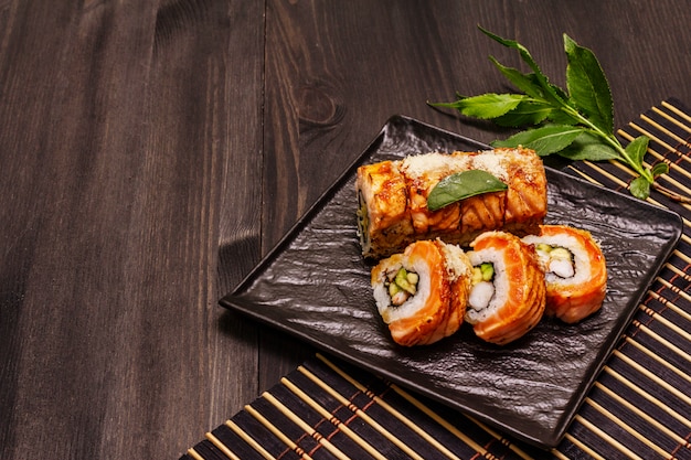 Foto gegrilde sushi met tijgergarnalen. japans of koreaans broodje met verschillende verse ingrediënten. trendy zwarte achtergrond