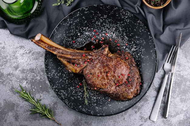 Gegrilde varkenssteak met bot in saus op zwarte plaat