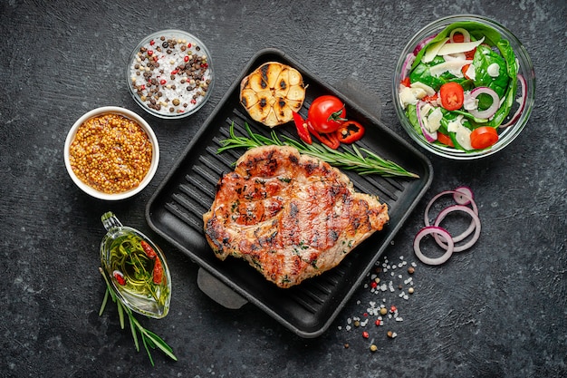 gegrilde varkenssteak met kruiden en frisse salade. Bovenaanzicht