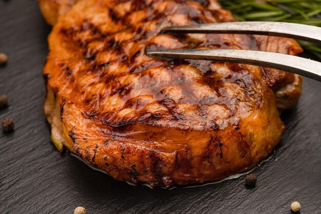 Gegrilde varkenssteak met rozemarijnzout en peper op een zwarte stenen plaat