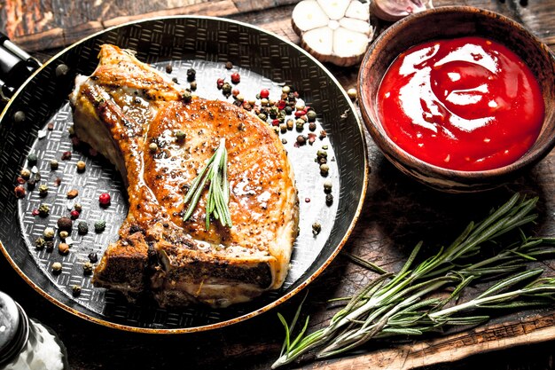 Gegrilde varkenssteak met tomatensaus. Op houten achtergrond.