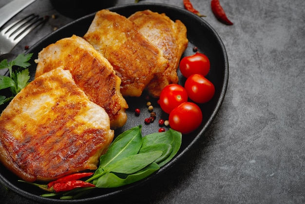 Gegrilde varkenssteaks in een pan met kruiden met kopieerruimte