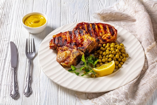 Gegrilde varkenssteaks met gekookte doperwtjes